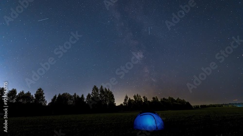Time Lapse of Milky Way Moving over blue Glowing Tent. Night Starry Sky 