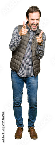 Middle age handsome man wearing winter vest pointing fingers to camera with happy and funny face. Good energy and vibes.