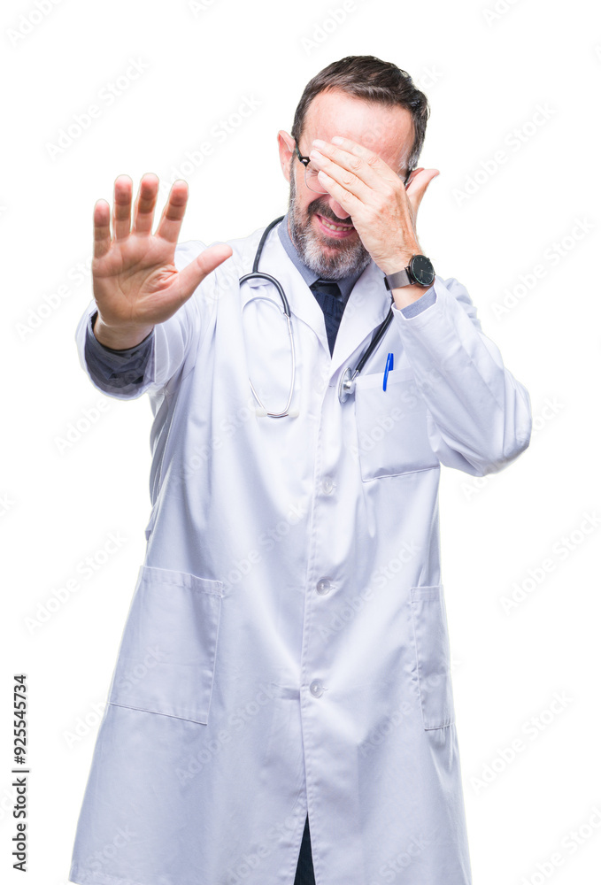 Middle age senior hoary doctor man wearing medical uniform isolated background covering eyes with hands and doing stop gesture with sad and fear expression. Embarrassed and negative concept. Middle age senior hoary doctor man wearing medical uniform isolated background covering eyes with hands and doing stop gesture with sad and fear expression. Embarrassed and negative concept.