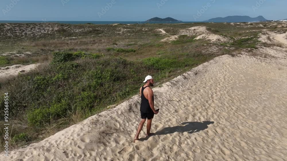 Man walking and running on sand dunes near the beach. Aerial image with drone following the man. Image from above. Health concept.