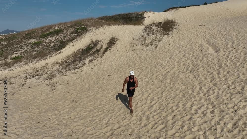 Man walking and running on sand dunes near the beach. Aerial image with drone following the man. Image from above. Health concept. Man walking and running on sand dunes near the beach. Aerial image with drone following the man. Image from above. Health concept.