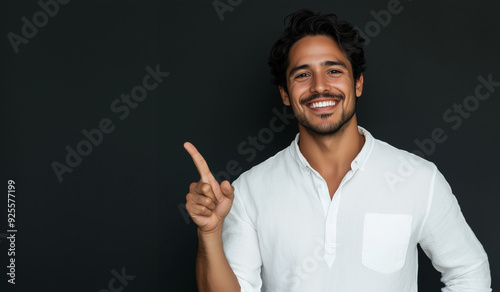 Studio portrait of A handsome latin man with a smile on his face pointing at an empty space wearing casual clothes isolated on a colored background for advertising or just copy space