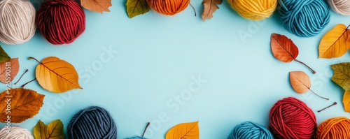 A colorful arrangement of yarn balls and autumn leaves on a blue background, perfect for crafting and creative projects.