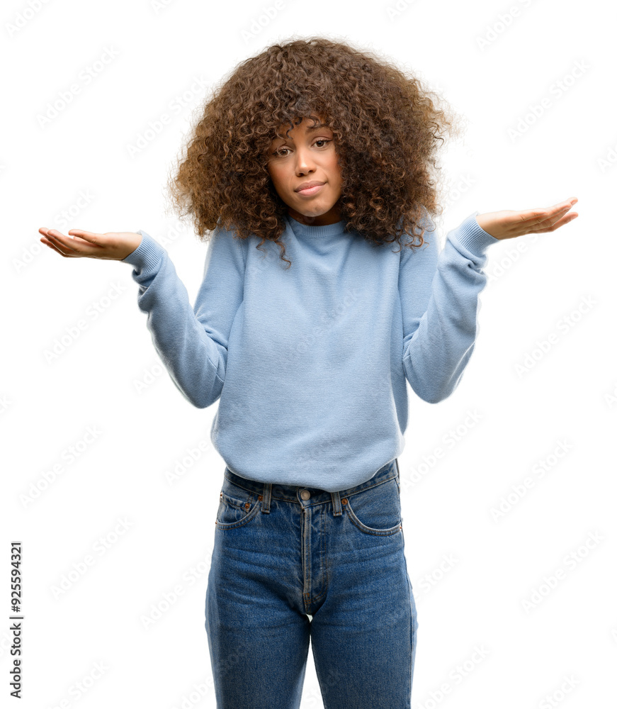 African american woman wearing a sweater clueless and confused expression with arms and hands raised. Doubt concept. African american woman wearing a sweater clueless and confused expression with arms and hands raised. Doubt concept.