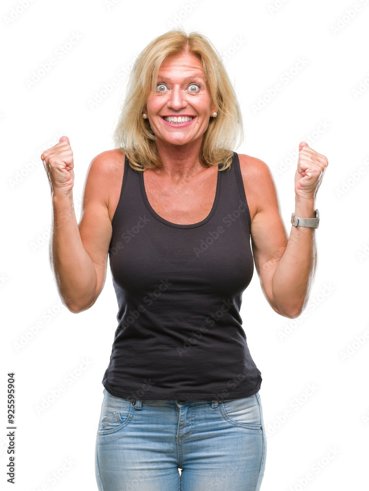 Middle age blonde woman over isolated background celebrating surprised and amazed for success with arms raised and open eyes. Winner concept. Middle age blonde woman over isolated background celebrating surprised and amazed for success with arms raised and open eyes. Winner concept.