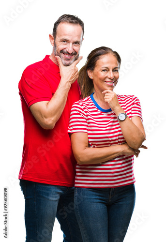 Middle age hispanic couple in love over isolated background looking confident at the camera with smile with crossed arms and hand raised on chin. Thinking positive.