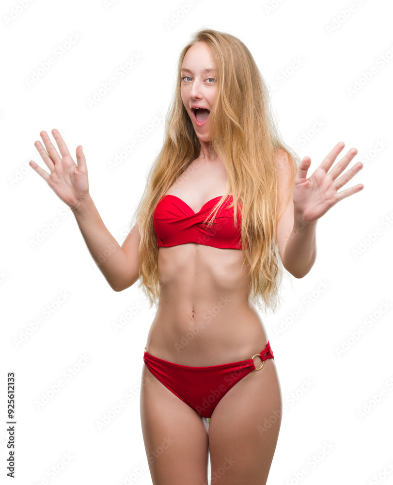 Blonde teenager woman wearing red bikini afraid and terrified with fear expression stop gesture with hands, shouting in shock. Panic concept. Blonde teenager woman wearing red bikini afraid and terrified with fear expression stop gesture with hands, shouting in shock. Panic concept.