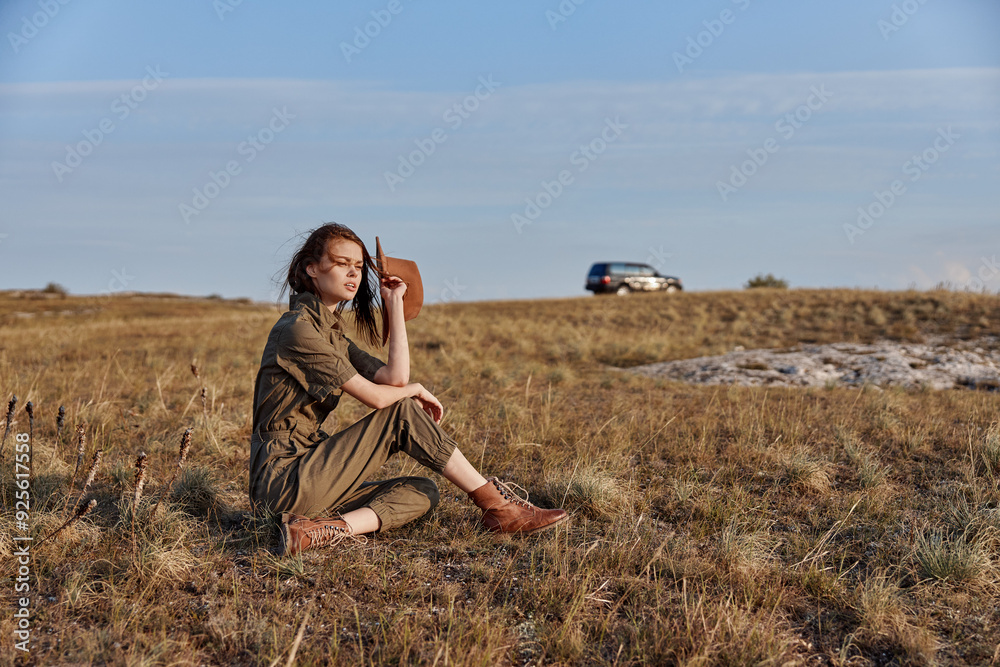 Woman sitting in a field with gun, car in background solitude and danger in nature Woman sitting in a field with gun, car in background solitude and danger in nature