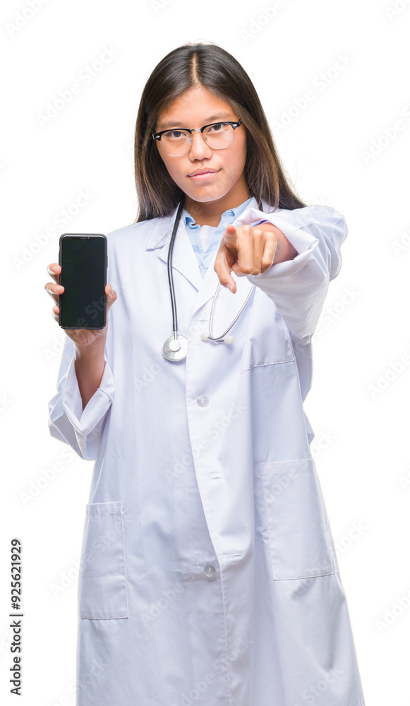 Young asian doctor woman holding smartphone over isolated background pointing with finger to the camera and to you, hand sign, positive and confident gesture from the front Young asian doctor woman holding smartphone over isolated background pointing with finger to the camera and to you, hand sign, positive and confident gesture from the front
