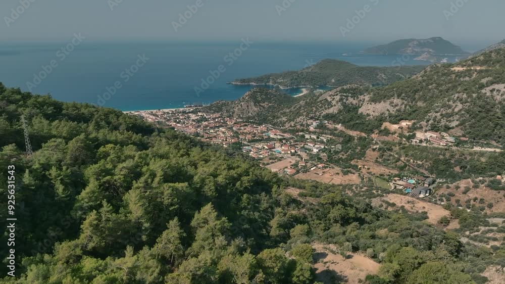 Aerial view of a mountainous coastal town, surrounded by lush greenery and overlooking the serene blue waters of the sea. Aerial view of a mountainous coastal town, surrounded by lush greenery and overlooking the serene blue waters of the sea.