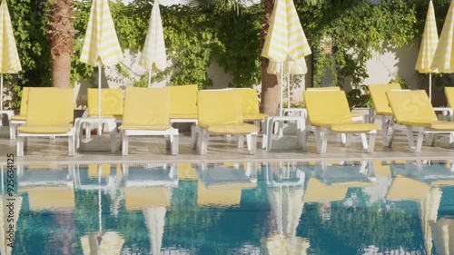 A row of yellow sun loungers lined up beside a clear blue pool, ready for a relaxing day in the sun.