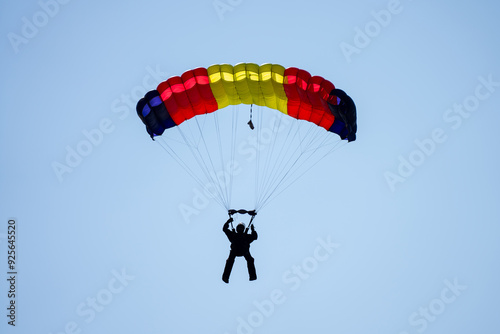 Person flying bright parachute alone in blue sky