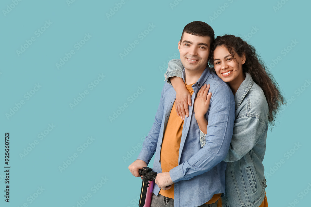 Happy young couple with modern electric kick scooter on blue background Happy young couple with modern electric kick scooter on blue background