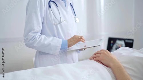 Doctor consulting patient with digital tablet in hospital room. Healthcare professional providing care