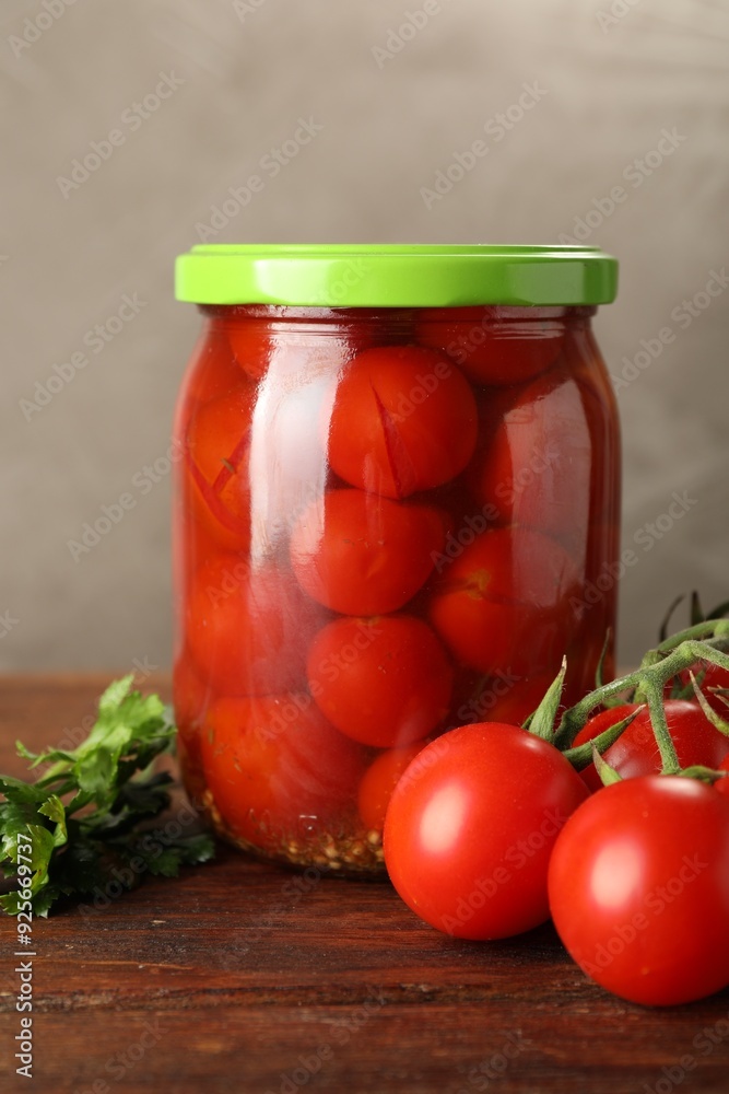 Tasty pickled tomatoes in jar and fresh ingredients on wooden table, closeup Tasty pickled tomatoes in jar and fresh ingredients on wooden table, closeup