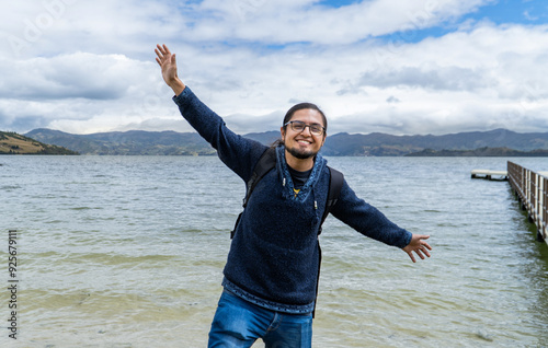 latin man traveler in a natural landscape and lagoon with open arms photo