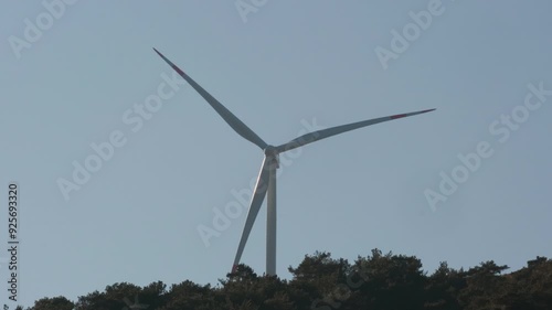 Turkey - November 10 2023: Wind turbines standing tall on a hilltop, surrounded by trees, capturing a moment of renewable energy in a natural landscape.