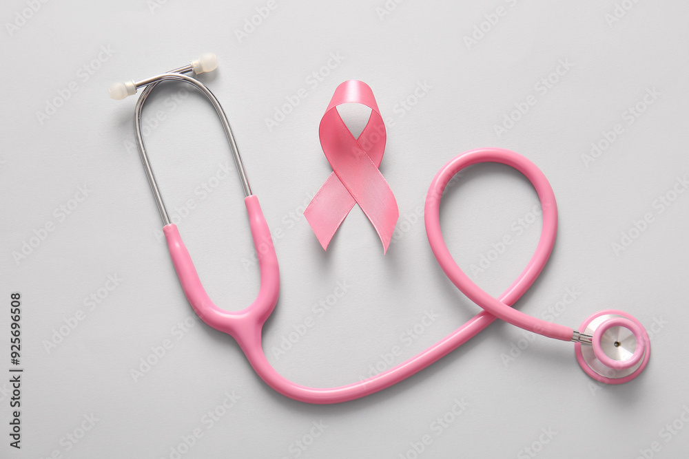 Fototapeta premium Stethoscope and pink ribbon on grey background. Breast cancer awareness concept