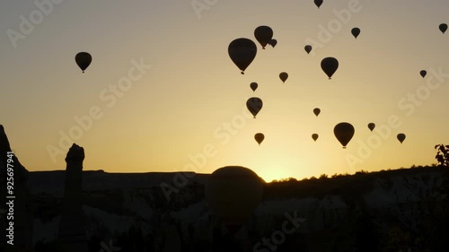 Nevşehir, Cappadocia - November 2 2022: Hot air balloons soaring in the sky during sunrise, creating a peaceful scene against the vibrant sunrise sky.