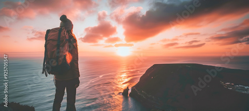 Backpacker Standing on Cliff Edge at Sunset photo