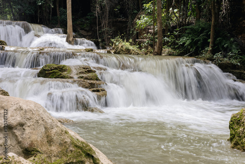 A mesmerizing waterfall cascades over smooth rocks, surrounded by lush greenery, creating a tranquil oasis where the gentle flow calms the senses and invites exploration.