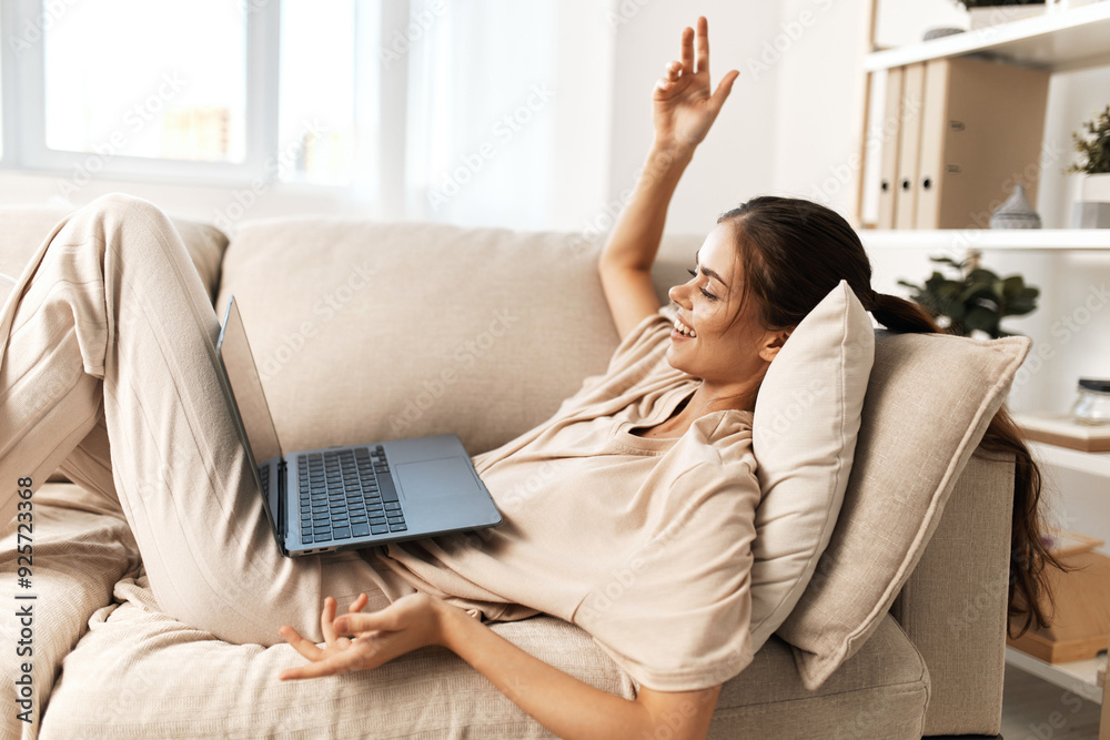 Smiling woman working on laptop in cozy home office, surrounded by modern technology and comfortable surroundings Smiling woman working on laptop in cozy home office, surrounded by modern technology and comfortable surroundings
