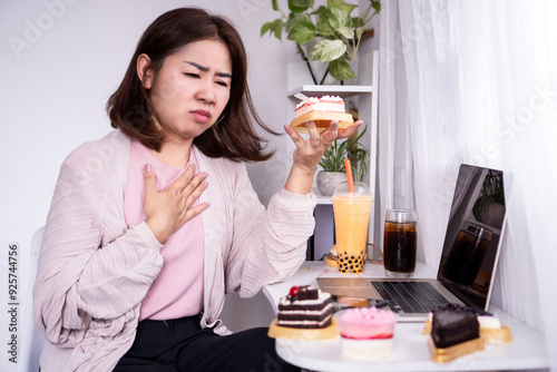 Asian woman suffering from acid reflux, heartburn, or GERD after overeating sweets desserts, indigestion concept photo