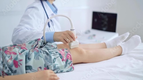 Doctor and kid patient. Orthopedist performing ultrasound examination on a child's knee in a clinic. Medicine and health care photo