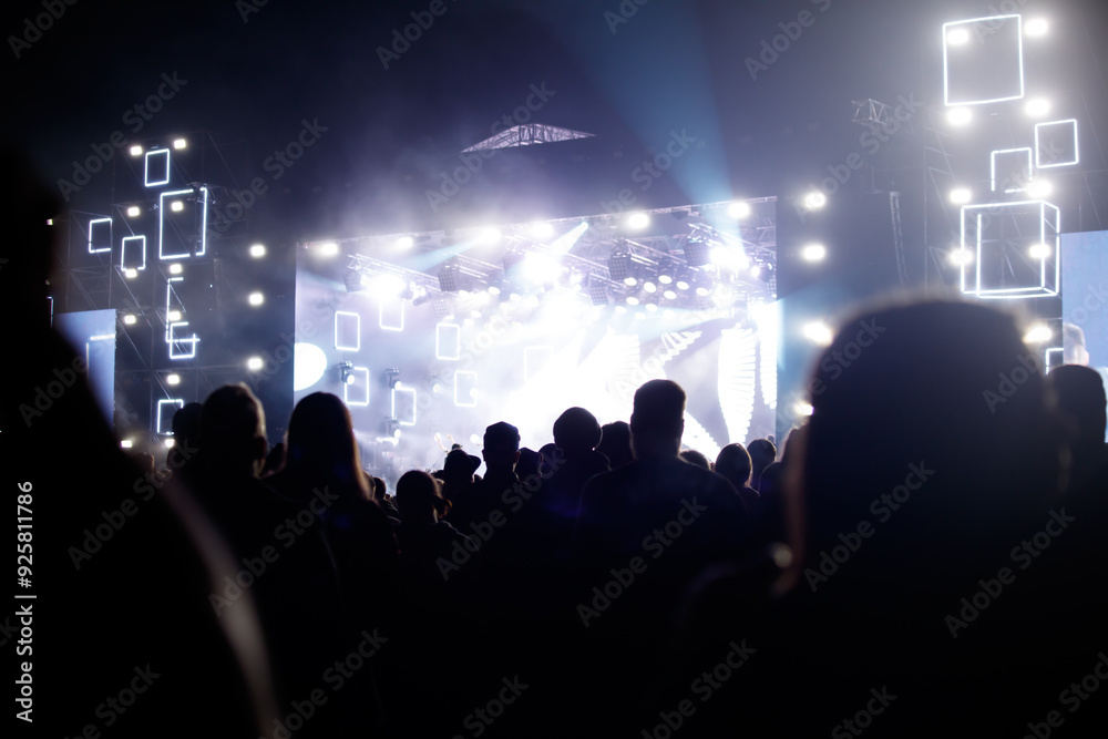 Silhouettes of spectators against a background of blue light at a concert Silhouettes of spectators against a background of blue light at a concert