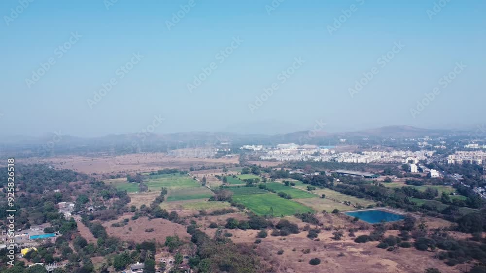 A countryside with fields, a pond, and buildings in the distance, aerial view, India A countryside with fields, a pond, and buildings in the distance, aerial view, India