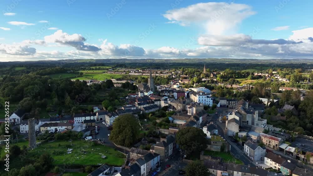 Clones Town, County Monaghan, Ireland, April 2023. Drone pulls backwards across old buildings revealing the Round Tower cemetery nestled between homes and businesses. Clones Town, County Monaghan, Ireland, April 2023. Drone pulls backwards across old buildings revealing the Round Tower cemetery nestled between homes and businesses.
