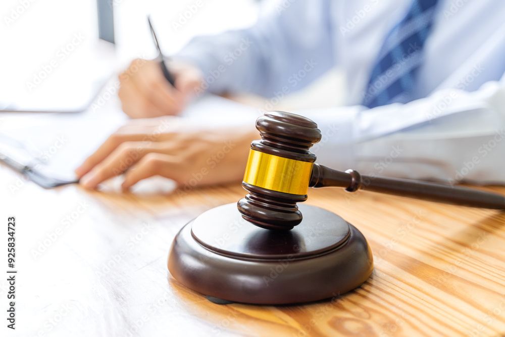 Close up of court gavel with blurred working male lawyer in background Close up of court gavel with blurred working male lawyer in background