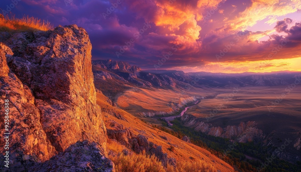 Fototapeta premium Panoramic view of a mountain landscape at sunset during golden hour, with the setting sun casting long shadows across the peaks, the sky ablaze with rich hues of orange, red, and purple, and a river