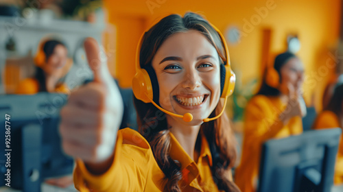  A smiling girl in a yellow headset gives a thumbs-up while working in a call center, with her colleagues in the background also making the same gesture