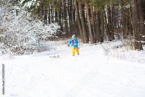 Cute little boy running in winter forest. Kid having fun outdoors.