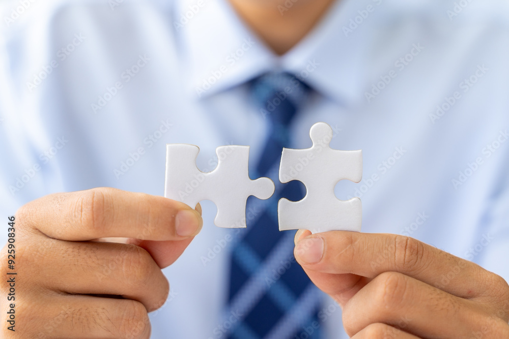 Close up hands of a businessman holding 2 jigsaw puzzle piecess trying to put them together Close up hands of a businessman holding 2 jigsaw puzzle piecess trying to put them together