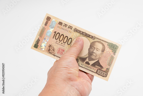Man's hand holding new Japan 10,000 yen banknote isolated on white background