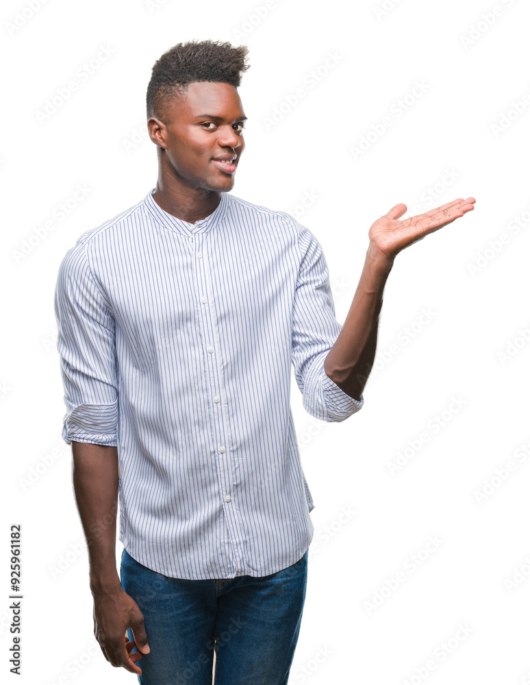 Young african american man over isolated background smiling cheerful presenting and pointing with palm of hand looking at the camera. Young african american man over isolated background smiling cheerful presenting and pointing with palm of hand looking at the camera.