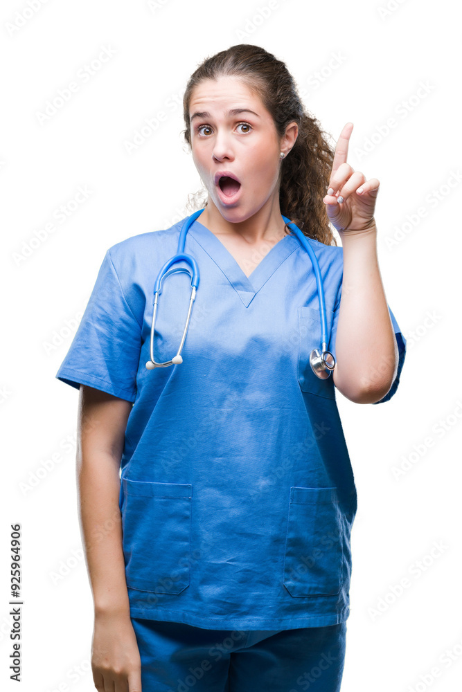 Young brunette doctor girl wearing nurse or surgeon uniform over isolated background pointing finger up with successful idea. Exited and happy. Number one. Young brunette doctor girl wearing nurse or surgeon uniform over isolated background pointing finger up with successful idea. Exited and happy. Number one.