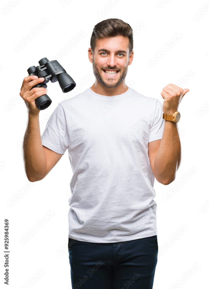 Young handsome man looking through binoculars over isolated background pointing and showing with thumb up to the side with happy face smiling Young handsome man looking through binoculars over isolated background pointing and showing with thumb up to the side with happy face smiling