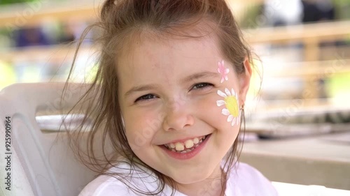 The artist makes a drawing on the girl's face with a face painting. 