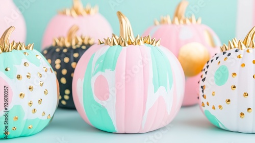 group of stylishly painted pumpkins in soft pastel colors like mint green, pink, and white, along with deep black. Each pumpkin is adorned with metallic gold and silver studs photo