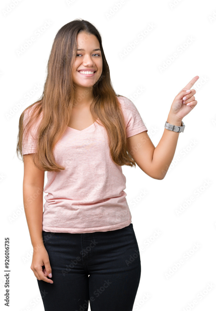 Young beautiful brunette woman wearing pink t-shirt over isolated background with a big smile on face, pointing with hand and finger to the side looking at the camera. Young beautiful brunette woman wearing pink t-shirt over isolated background with a big smile on face, pointing with hand and finger to the side looking at the camera.