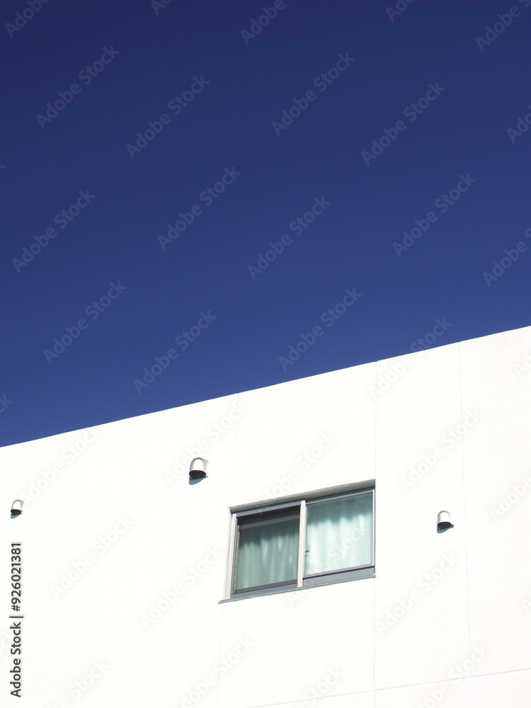 小窓のある白い壁と冬の青空