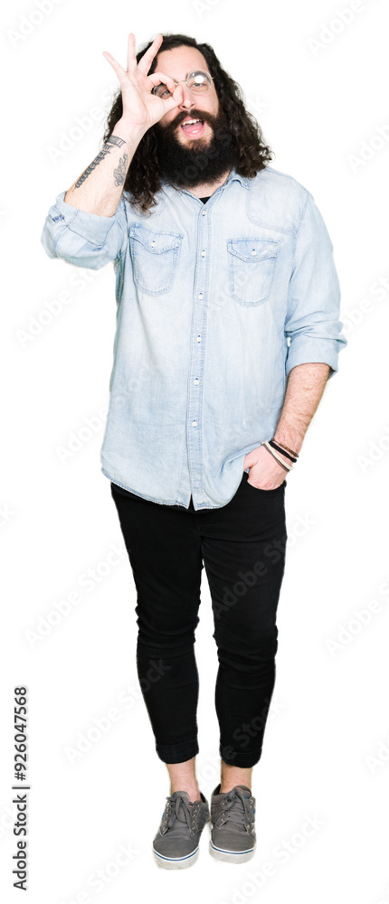 Young hipster man with long hair and beard wearing glasses doing ok gesture with hand smiling, eye looking through fingers with happy face. Young hipster man with long hair and beard wearing glasses doing ok gesture with hand smiling, eye looking through fingers with happy face.