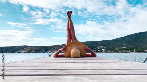 relaxed woman lifts her legs up lying on wooden pier
