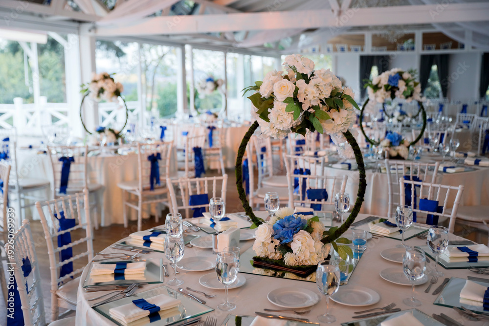 A beautifully decorated wedding reception with round tables adorned with white flowers and blue accents