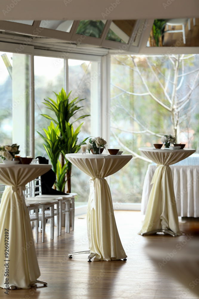 A stylish and contemporary event space with cocktail tables and white linens. The room is perfect for a wedding, corporate event, or social gathering