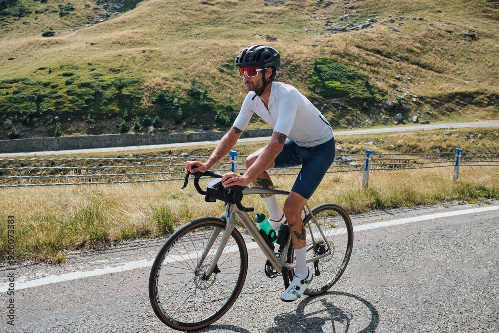 Man cyclist is training a bicycle. Sports motivation image.Good road for cycling. Man cyclist riding a gravel bike with a view of the mountains. Travel biking concept. Transfăgărășan road in Romania. Man cyclist is training a bicycle. Sports motivation image.Good road for cycling. Man cyclist riding a gravel bike with a view of the mountains. Travel biking concept. Transfăgărășan road in Romania.