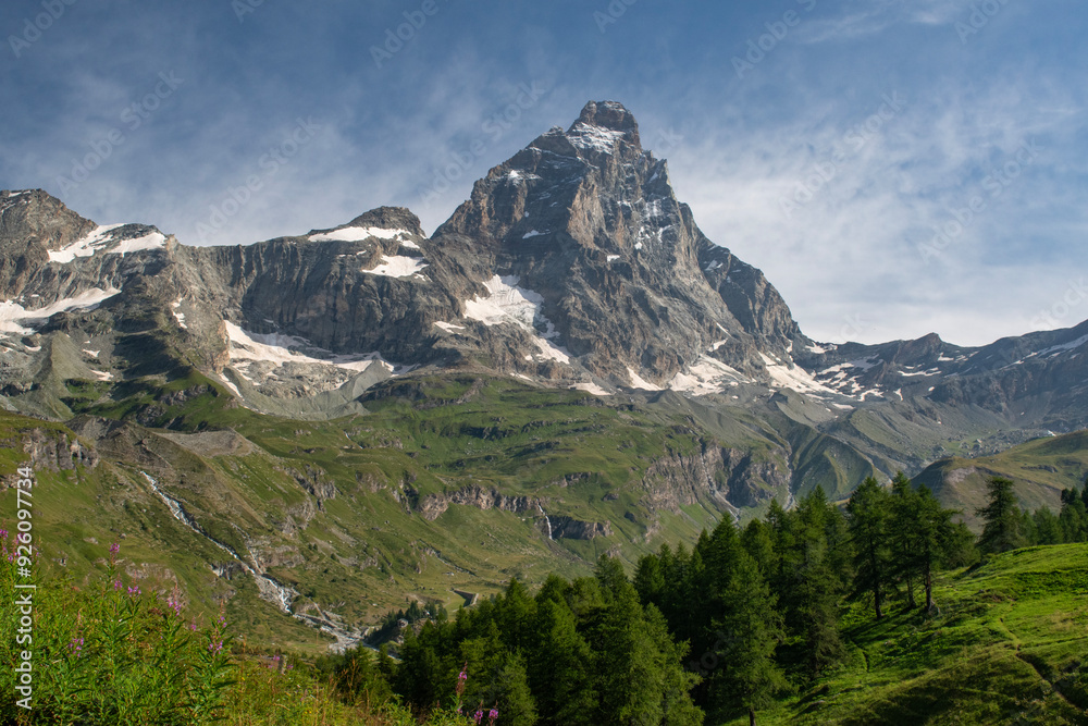 Valle d'Aosta, Italy, 08-15-2024: panoramic view of Cervino (Matterhorn), famous mountain of the Central Alps, 4,478 meters high, with the mountain range, green meadows and fir forests on a summer day Valle d'Aosta, Italy, 08-15-2024: panoramic view of Cervino (Matterhorn), famous mountain of the Central Alps, 4,478 meters high, with the mountain range, green meadows and fir forests on a summer day